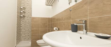 Une salle de bain moderne équipée d’un lavabo, de toilettes et d’une douche.