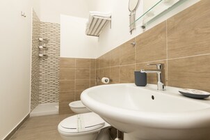 Un baño moderno con lavamanos, inodoro y ducha.
