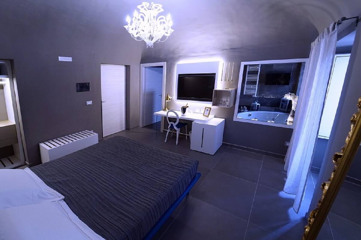 Una camera da letto moderna con un letto, una scrivania e un'ampia finestra.