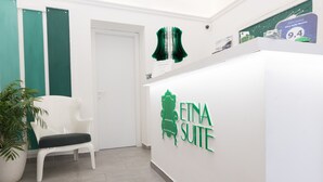 Un área de recepción con una silla blanca, una planta en maceta y un cartel en la pared que dice "EINA SUITE".