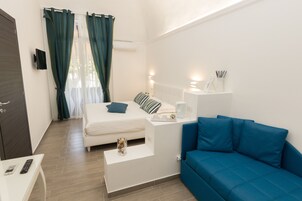 Una moderna camera d'albergo con un letto, un divano blu, un tavolino e una televisione.