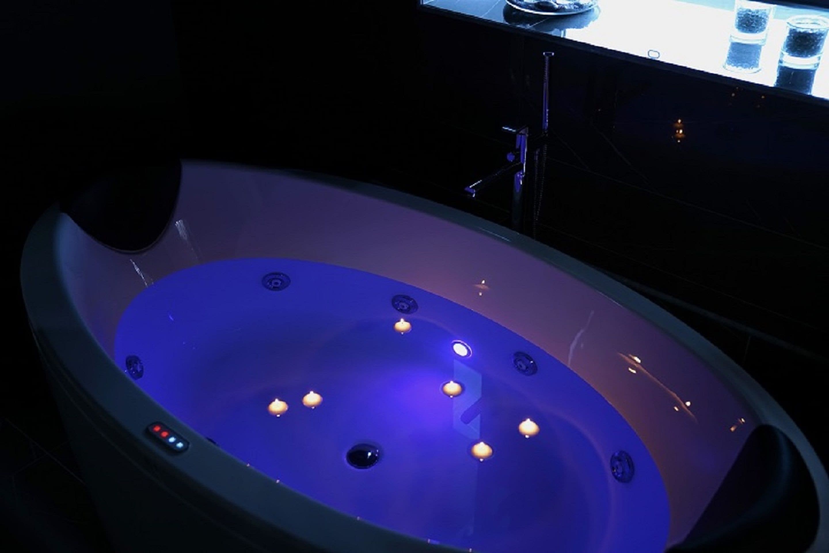 A bathtub with multiple jets and a control panel.