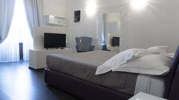 A modern hotel room with a large bed, a flat-screen TV, a desk, and a chair.