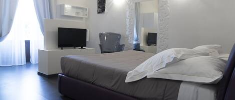 A modern hotel room with a large bed, a flat-screen TV, a desk, and a chair.