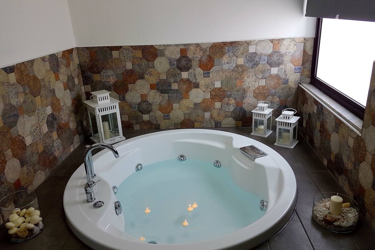 Un bagno con una vasca da bagno ampia, due candele accese e lanterne decorative.