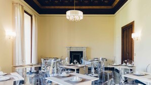 Un comedor con sillas traslúcidas, mesas blancas y una araña.