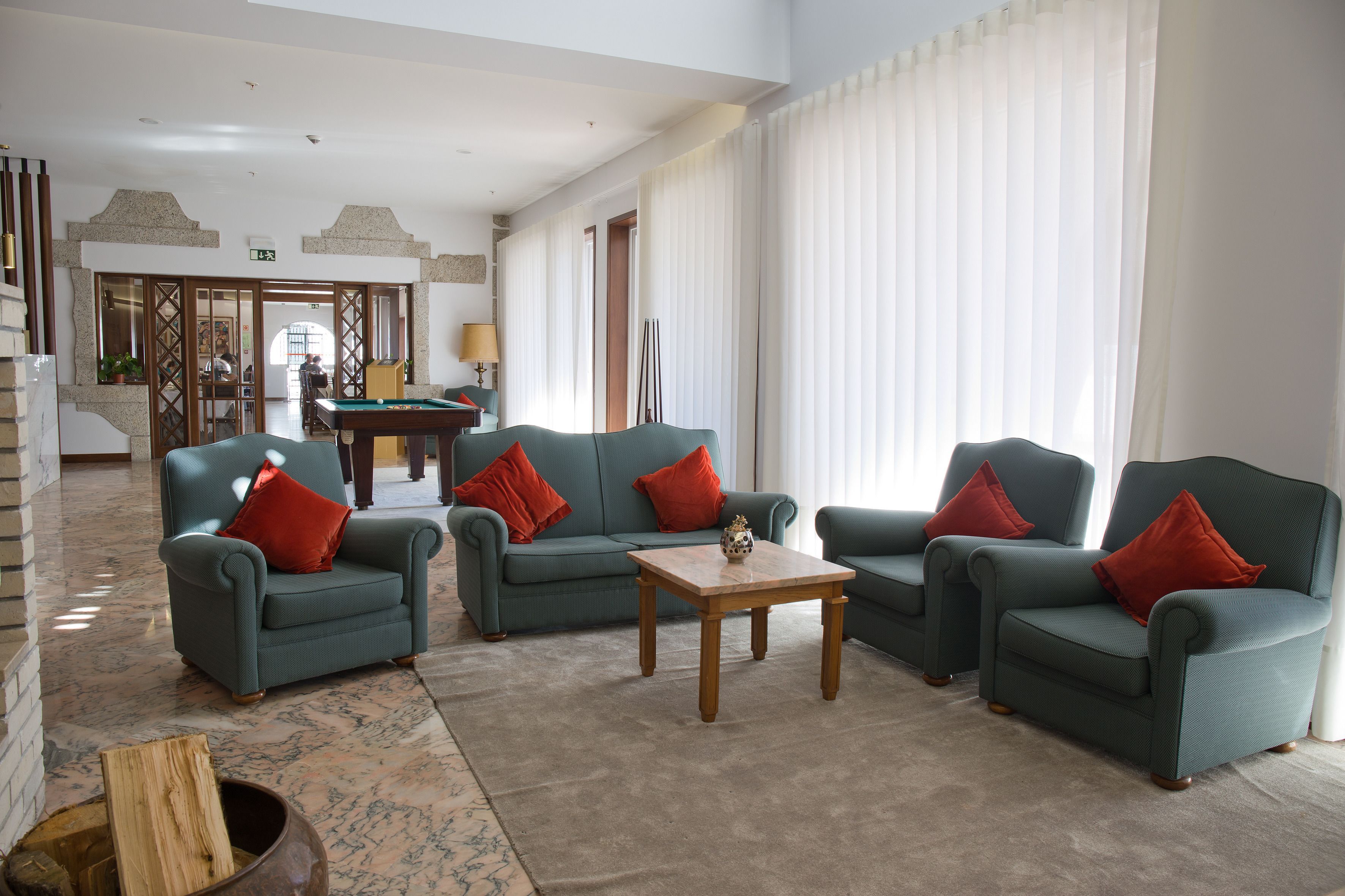Un lobby amplio con mesa de billar, dos sofás con cojines rojos y una mesa de centro de madera.