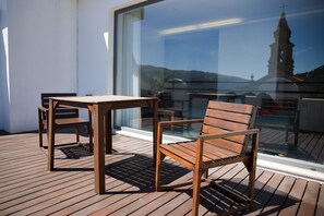 A wooden deck with two chairs and a table, overlooking a church with a bell tower. - Hotel São Bento da Porta Aberta & Spa (Terras de Bouro)
