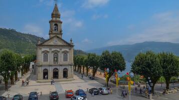 A church with a bell tower, surrounded by trees and parked cars.