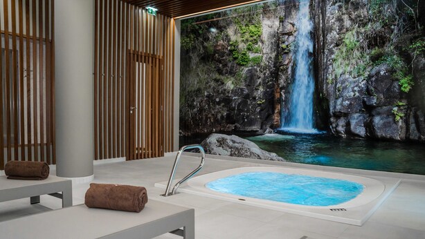 A spa area with a hot tub, wooden slats, and a waterfall mural. - Hotel São Bento da Porta Aberta & Spa (Terras de Bouro)