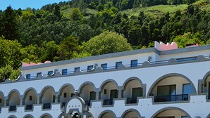 A building with multiple balconies and arched windows, surrounded by lush green hills. - Hotel São Bento da Porta Aberta & Spa (Terras de Bouro)