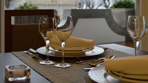 A dining table set with plates, glasses, and cutlery, with a view of a church through an arched window. - Hotel São Bento da Porta Aberta & Spa (Terras de Bouro)