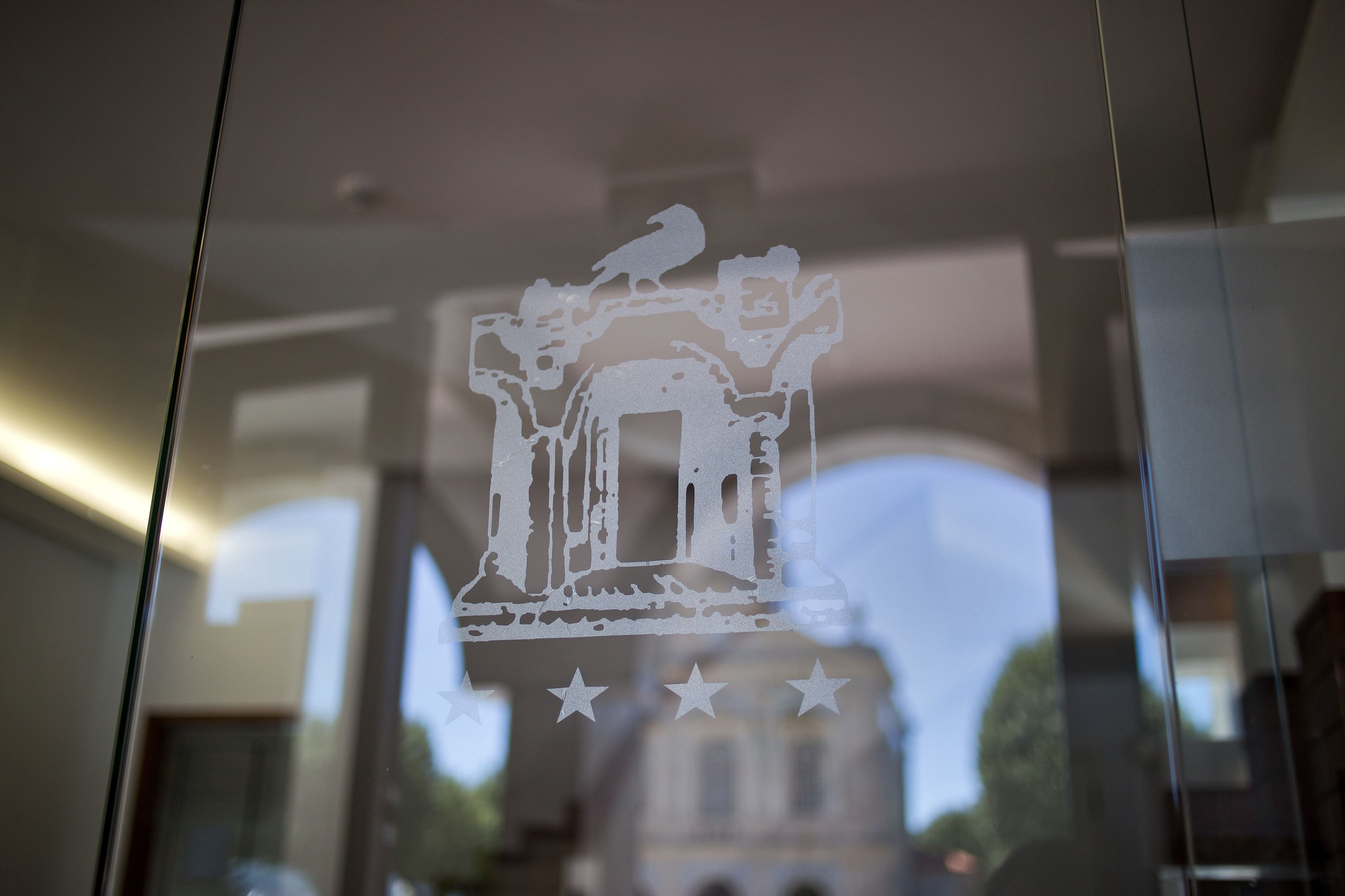 A glass window with a white paper cut-out of a building and a bird.