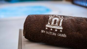 En ihopvikt, brun handduk med en logotyp för ett spa och texten ”SPA NATURE GERES” på en träyta.
