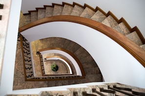 A spiral staircase with marble steps and wooden handrails.