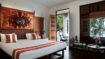 Un dormitorio amplio con una cama grande, un cabecero de madera, una mesita de noche y una silla junto a la ventana.