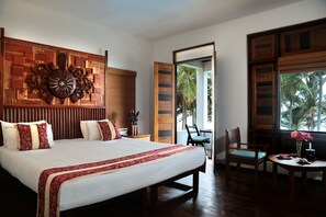 A spacious bedroom with a large bed, a wooden headboard, a bedside table, and a chair by the window.