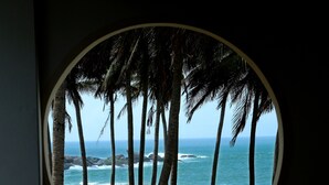 A view through a circular window of a beach with palm trees and the ocean.