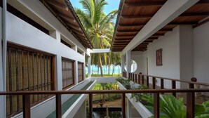 A corridor with a view of a pool and palm trees, leading to a beach.