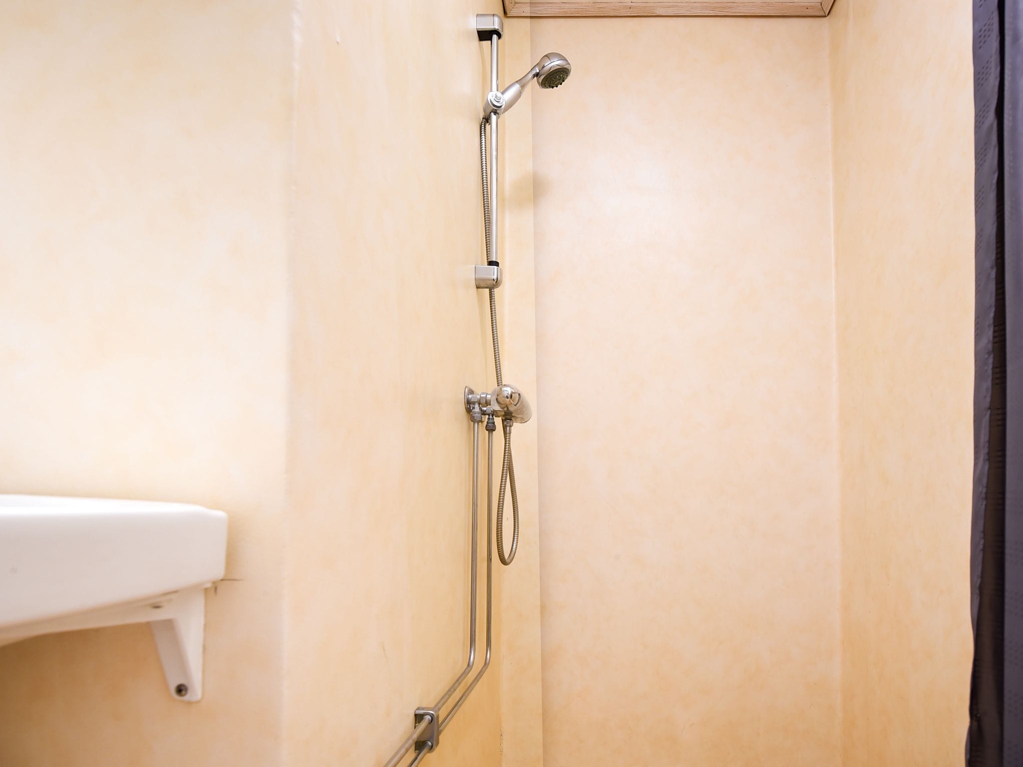 Ducha con cabezal de ducha de mano y otro fijo, instalados en una pared color beige.