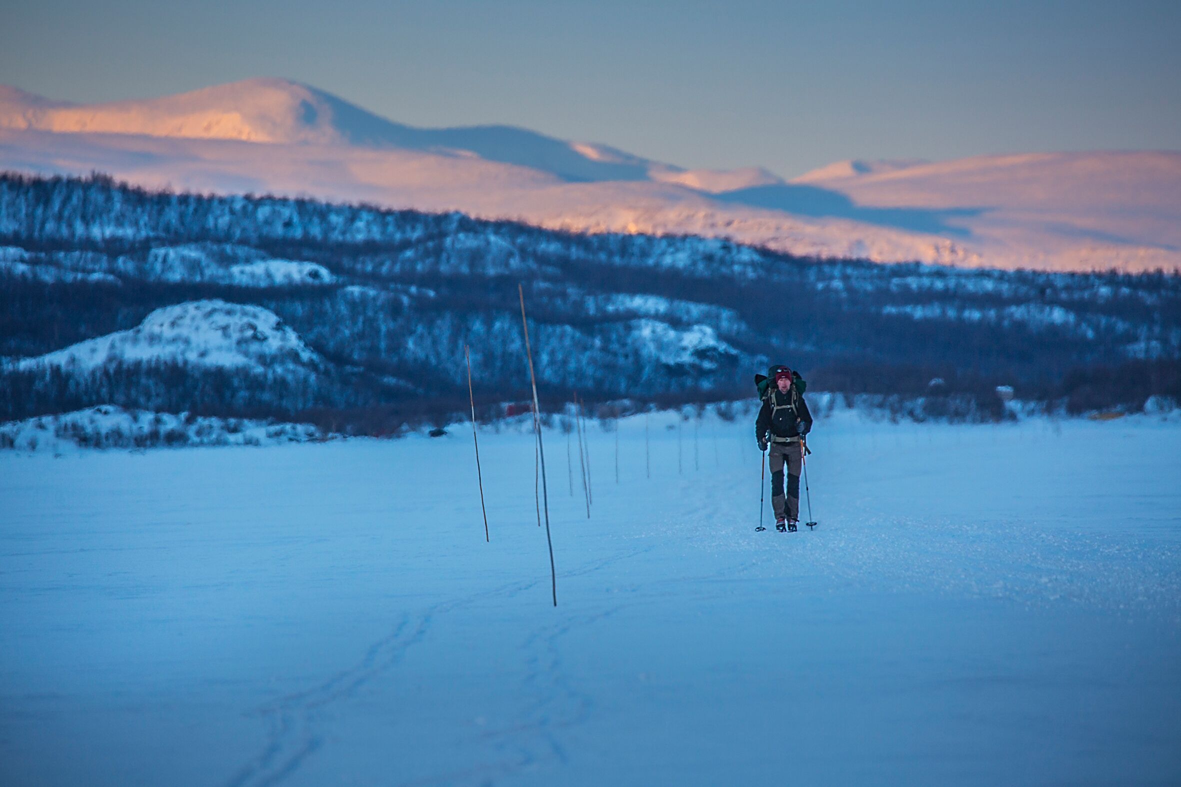 A person skiing in a snowy landscape with mountains in the background.