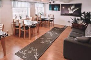 A dining area with a table and chairs, a sofa, and a rug.
