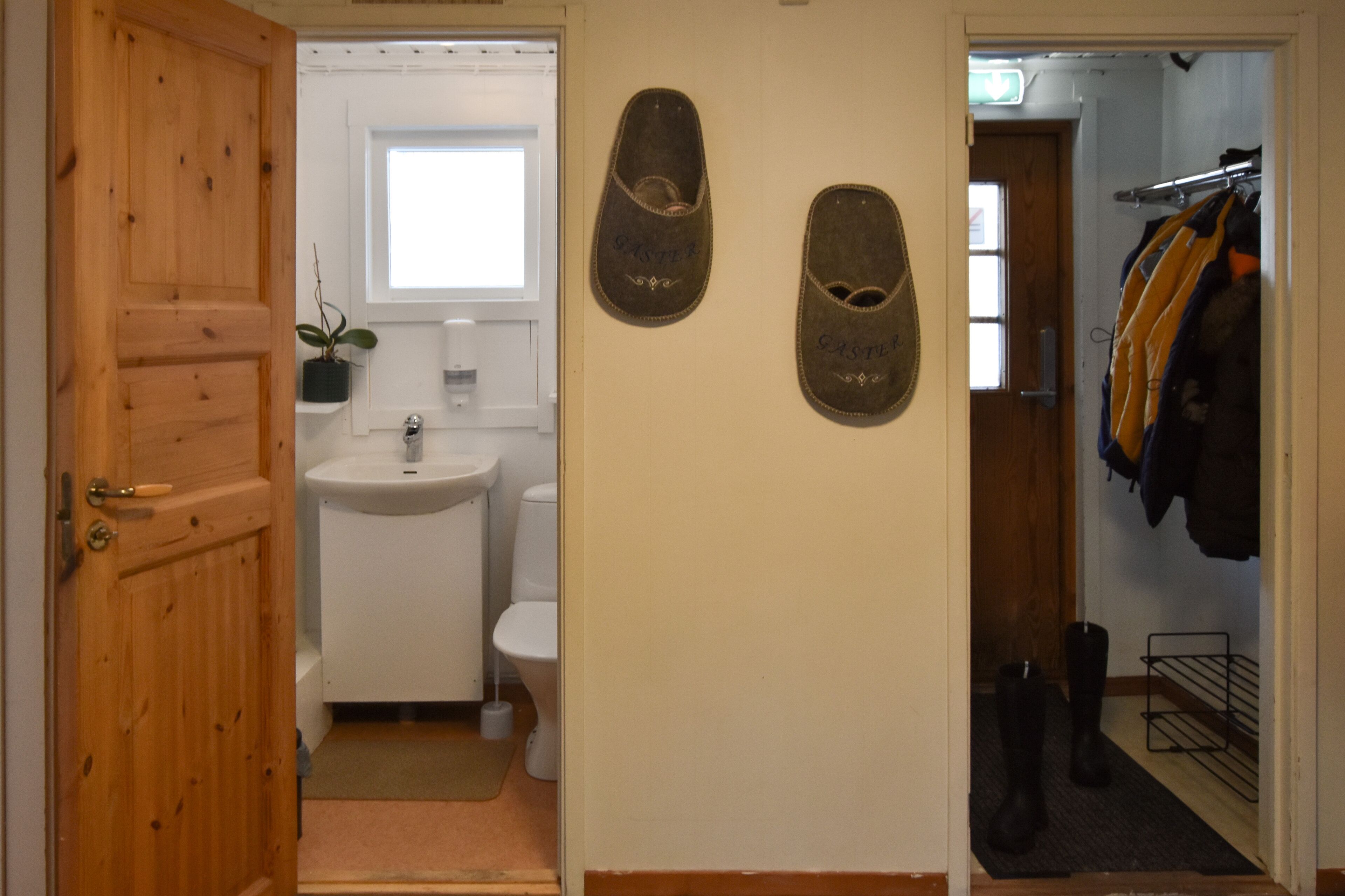 Puerta de madera que da a un baño con lavabo, inodoro y ventana.