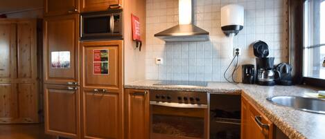 Une cuisine avec des meubles de rangement en bois, un four encastré, un four à micro-ondes et une cuisinière.