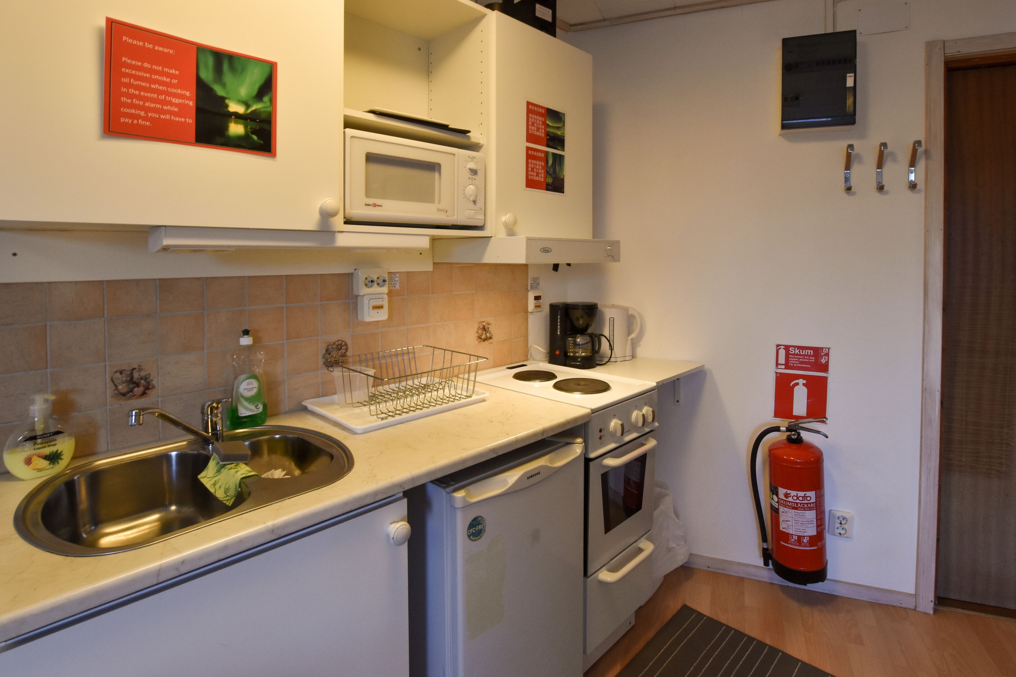 Cocina compacta con fregadero, microondas, estufa y horno. Hay un extintor de incendios montado en la pared.