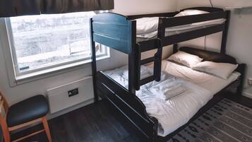 A bunk bed room with a window, a chair, and a radiator.