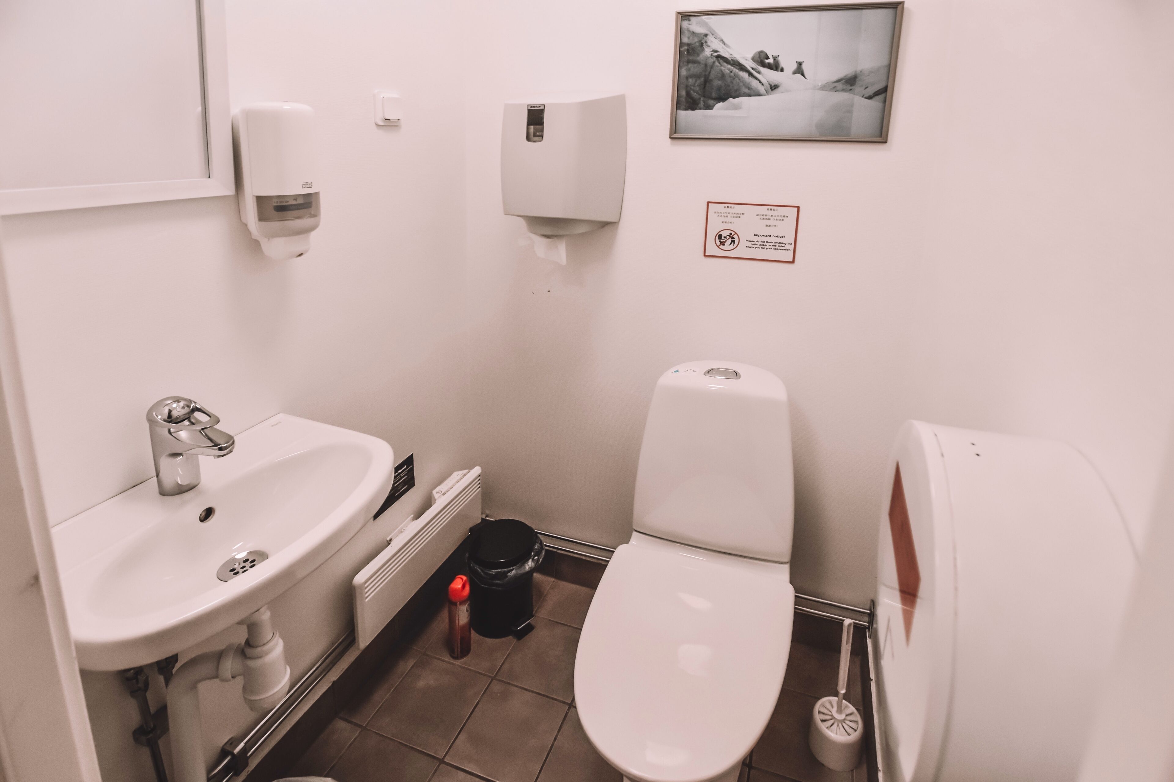A small, clean bathroom with a sink, toilet, and hand dryer.