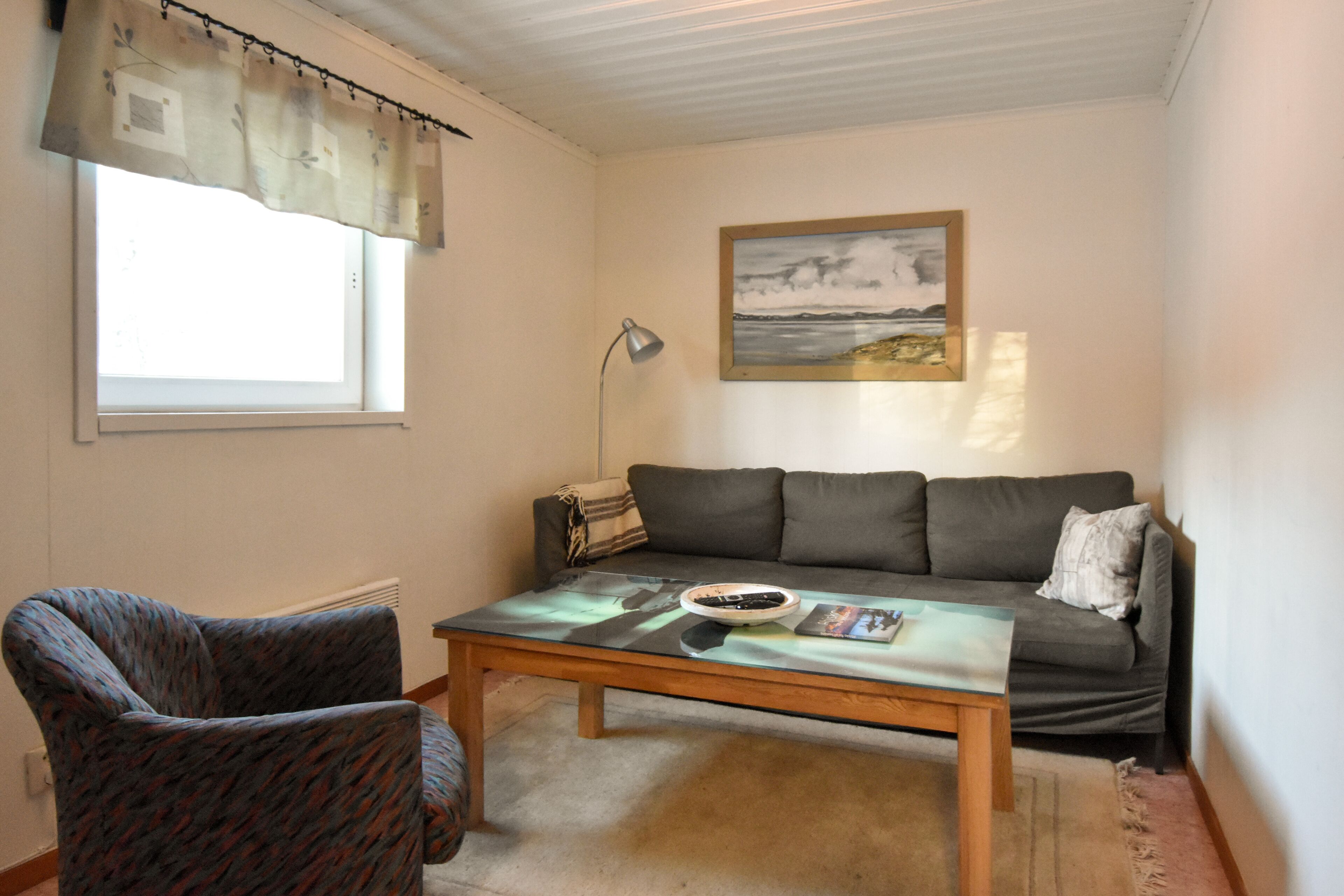 Ein Wohnzimmer mit Sofa, Sessel, Couchtisch und einem Gemälde an der Wand.
