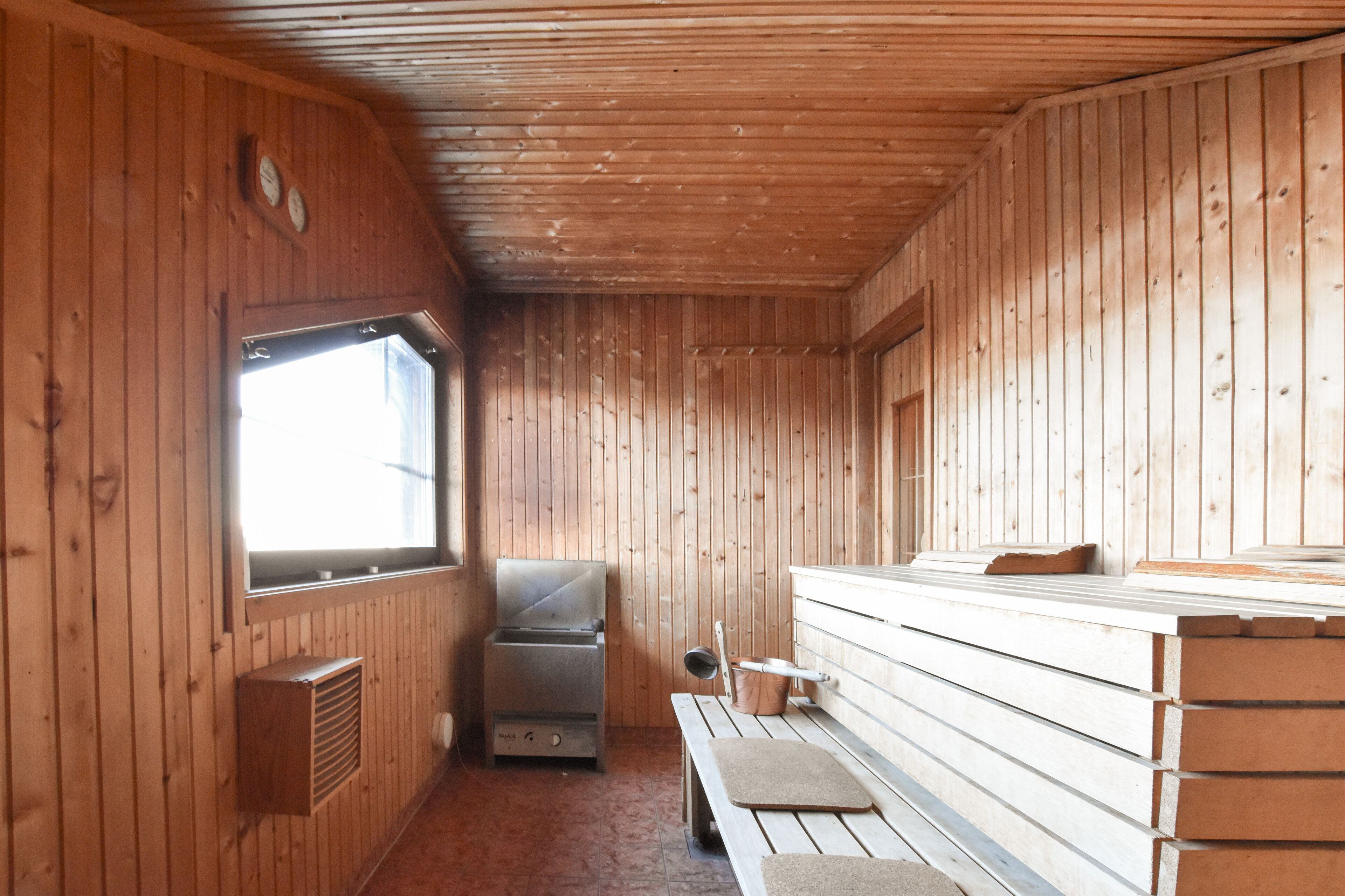 Een chalet met houten wanden, een bank, een barbecue en een raam.