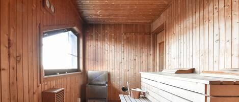 Uma cabana com paredes de madeira, um banco, uma churrasqueira e uma janela.
