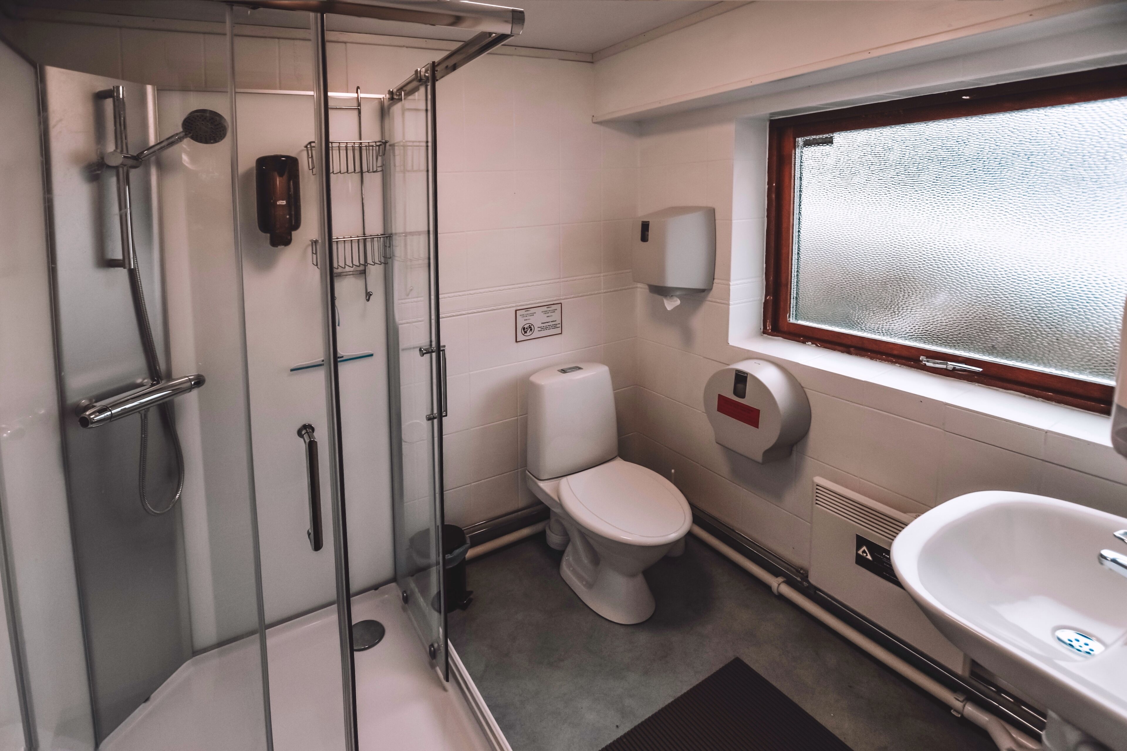 Un baño moderno con ducha vidriada, inodoro y lavamanos.