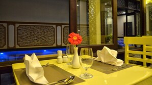 A dining table set with a vase, wine glass, and napkin. - River Suites Hoi An Hotel (Da Nang)