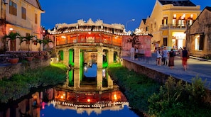 A traditional building with ornate architecture, a reflection in the water, and people walking nearby.