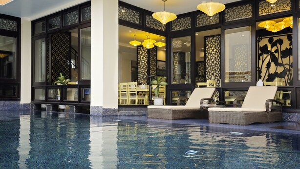 A pool area with lounge chairs and decorative lighting. - River Suites Hoi An Hotel (Da Nang)
