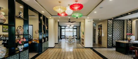 A hotel corridor with patterned flooring, decorative lanterns, and a view to the outside.