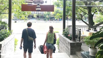 A man and a woman walking down a staircase towards a building with a covered entrance.