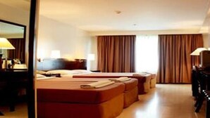 Una habitación de hotel con cama, escritorio, silla, cómoda y espejo.