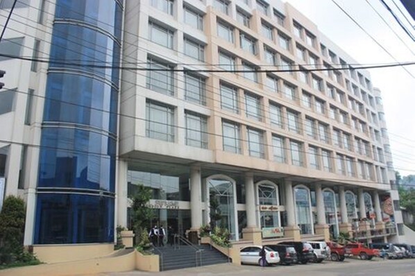 A multi-story hotel with a modern facade, large windows, and a covered entrance area.