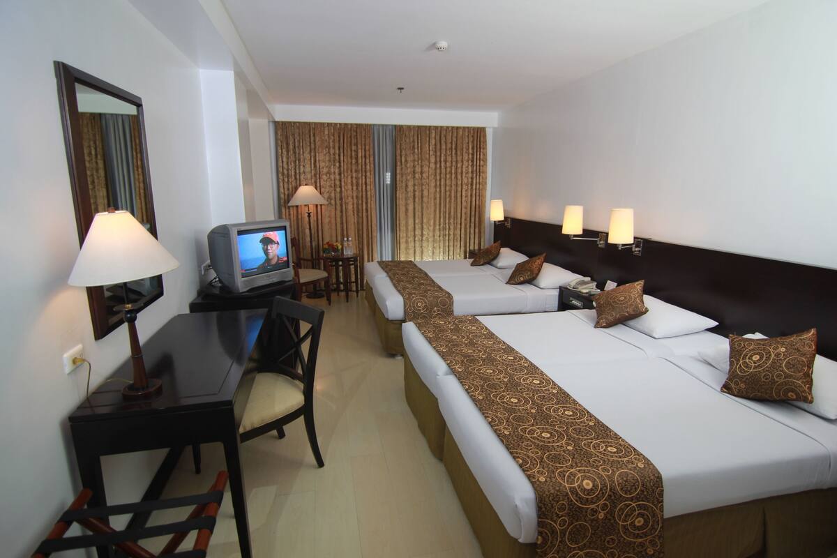 Een hotelkamer met twee bedden, een bureau, een televisie en een stoel.