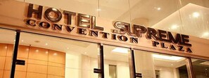 The exterior of Hotel Supreme Convention Plaza with a modern design and large glass entrance.