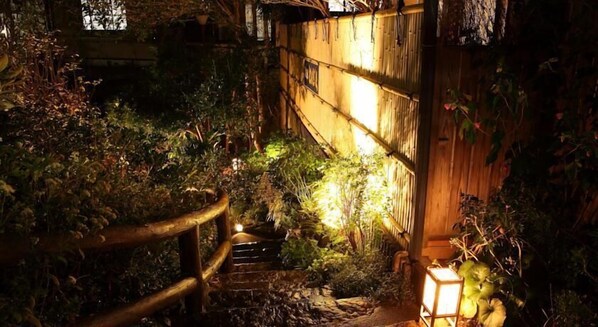 A wooden staircase leading to a bamboo structure with a lantern at the bottom.