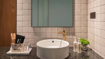Un baño moderno con un lavamanos grande, un espejo y un estante de madera con toallas.