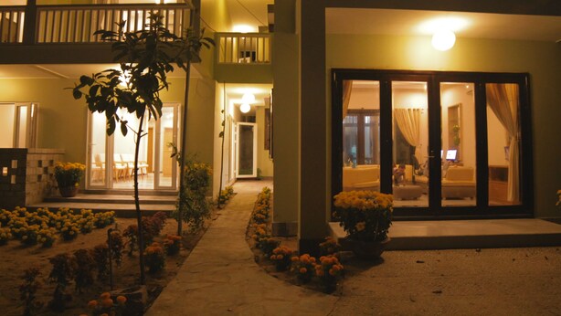 A hotel with a balcony, a garden with flowers, and a well-lit entrance. - Jolie Villa Hoi An (Da Nang)