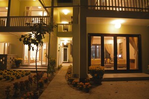 A hotel with a balcony, a garden with flowers, and a well-lit entrance. - Jolie Villa Hoi An (Da Nang)