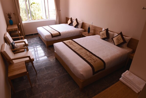 A hotel room with two single beds, a wooden chair, a small table, and a window with curtains. - Jolie Villa Hoi An (Da Nang)