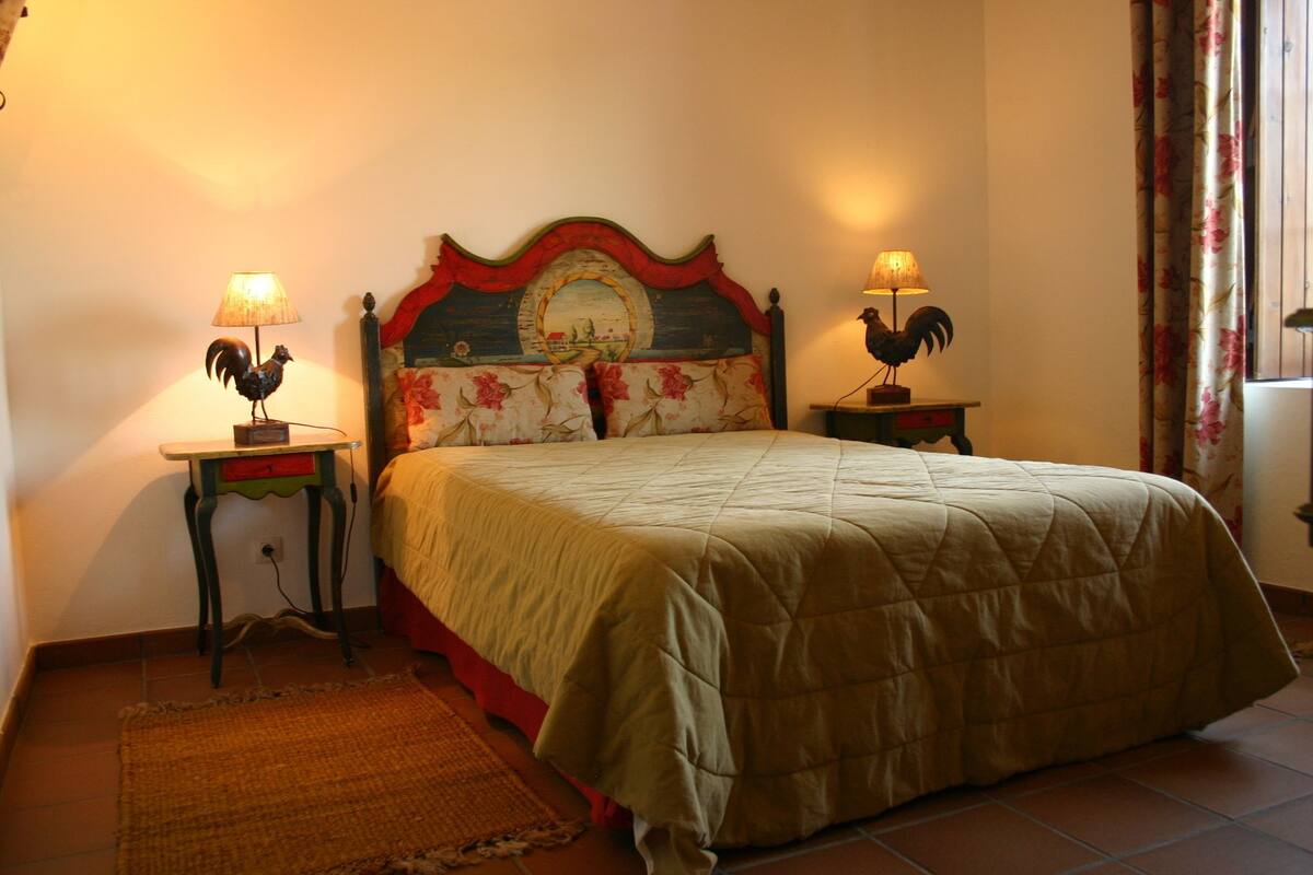 A bedroom with a bed, two nightstands, a lamp, a rug, and a decorative headboard.